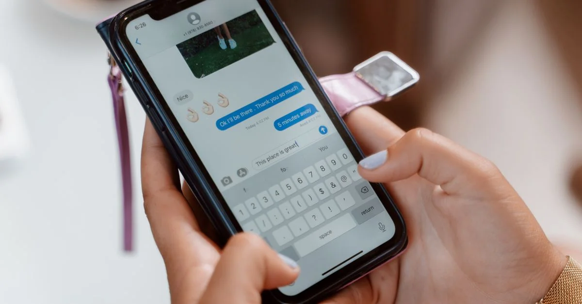 Femme tapant sur un smartphone, envoyant un message texte avec emoji.