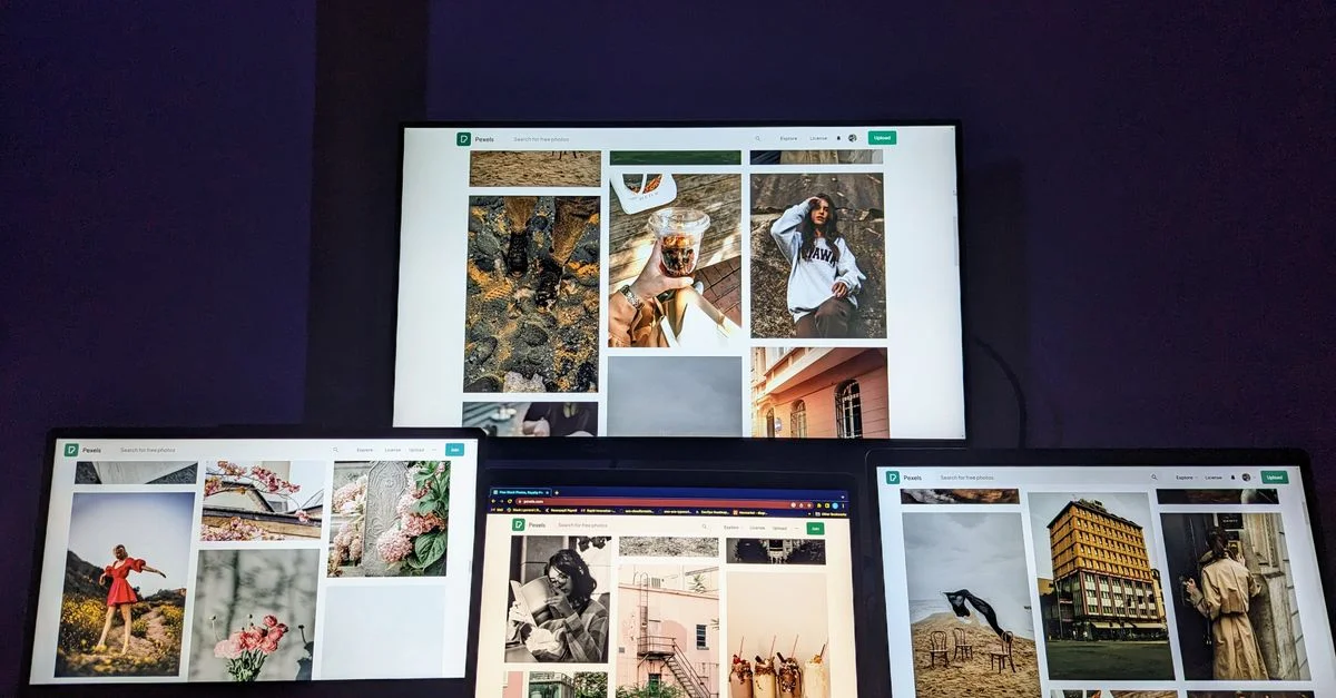 Un espace de travail high-tech avec trois ordinateurs portables et un moniteur affichant diverses images, mettant en avant la technologie et l'art numérique.