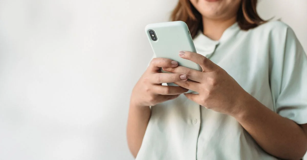 Gros plan d'une femme utilisant un smartphone à l'intérieur avec beaucoup d'espace pour le texte.