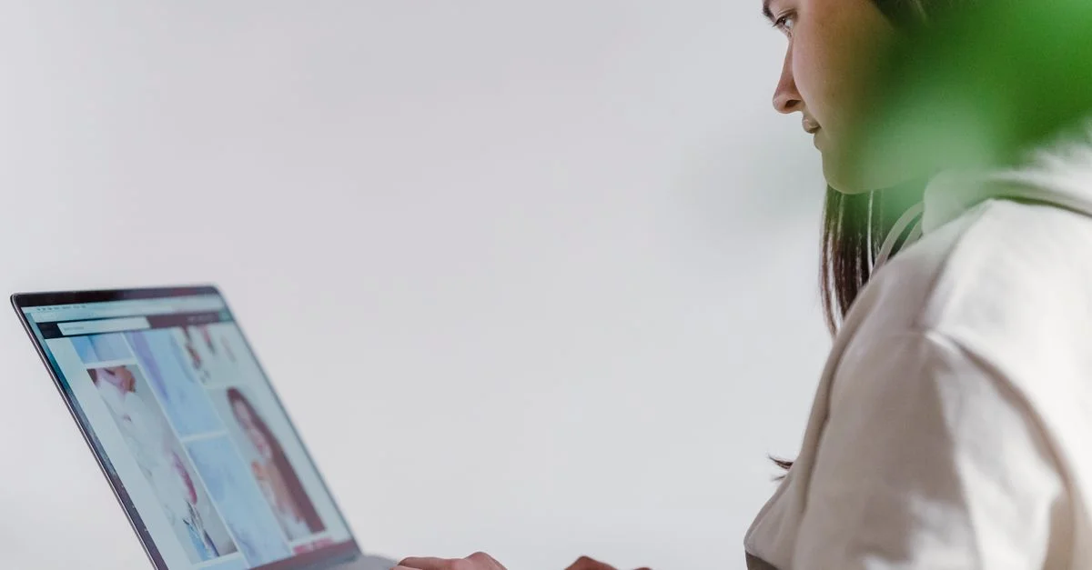 Femme concentrée utilisant un ordinateur portable dans un cadre intérieur calme, travaillant depuis chez elle.